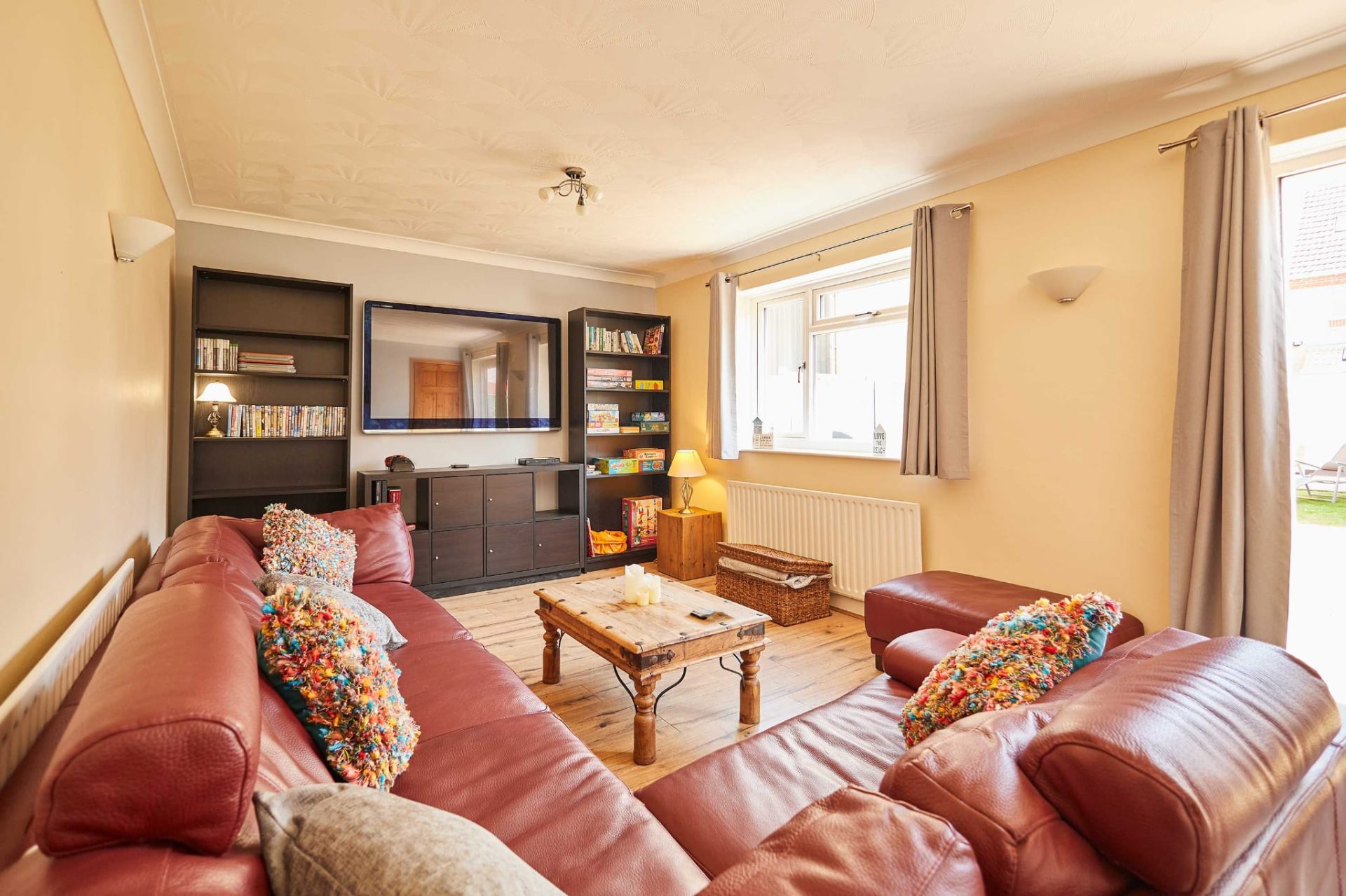 Bright living room with red leather sofas and bookshelves at Sea Breeze
